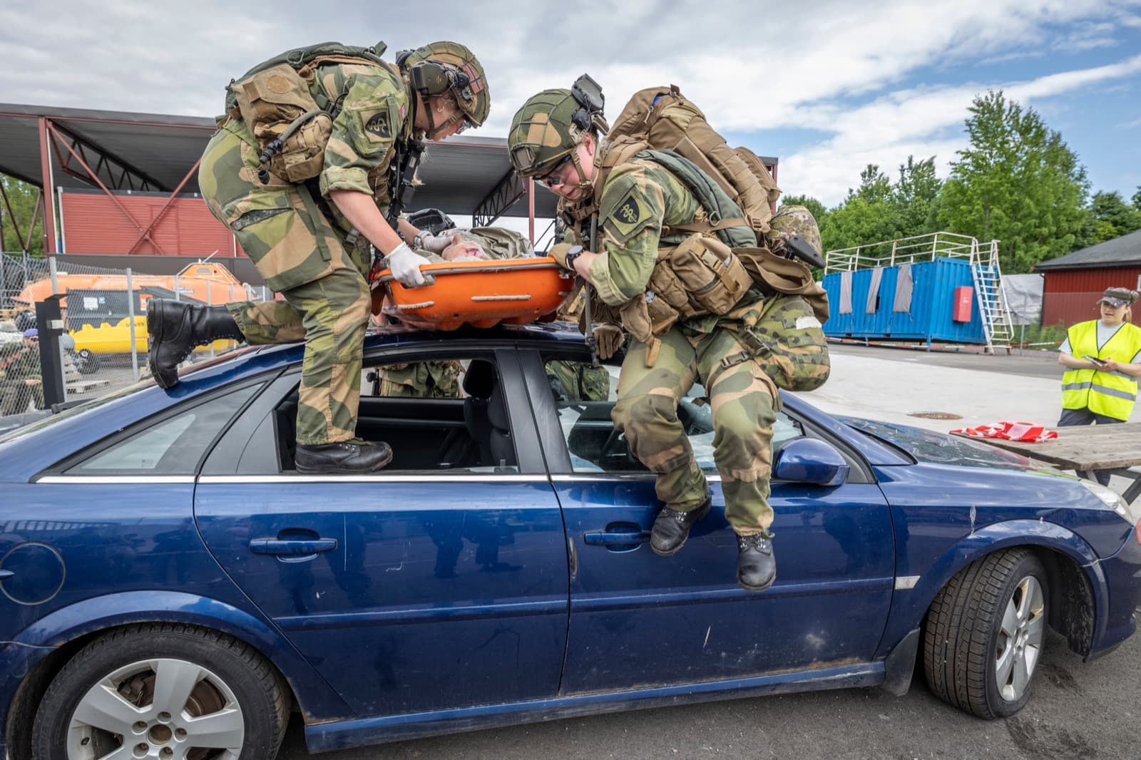 A team lifting a casualty in a stretcher over a car during NMC26